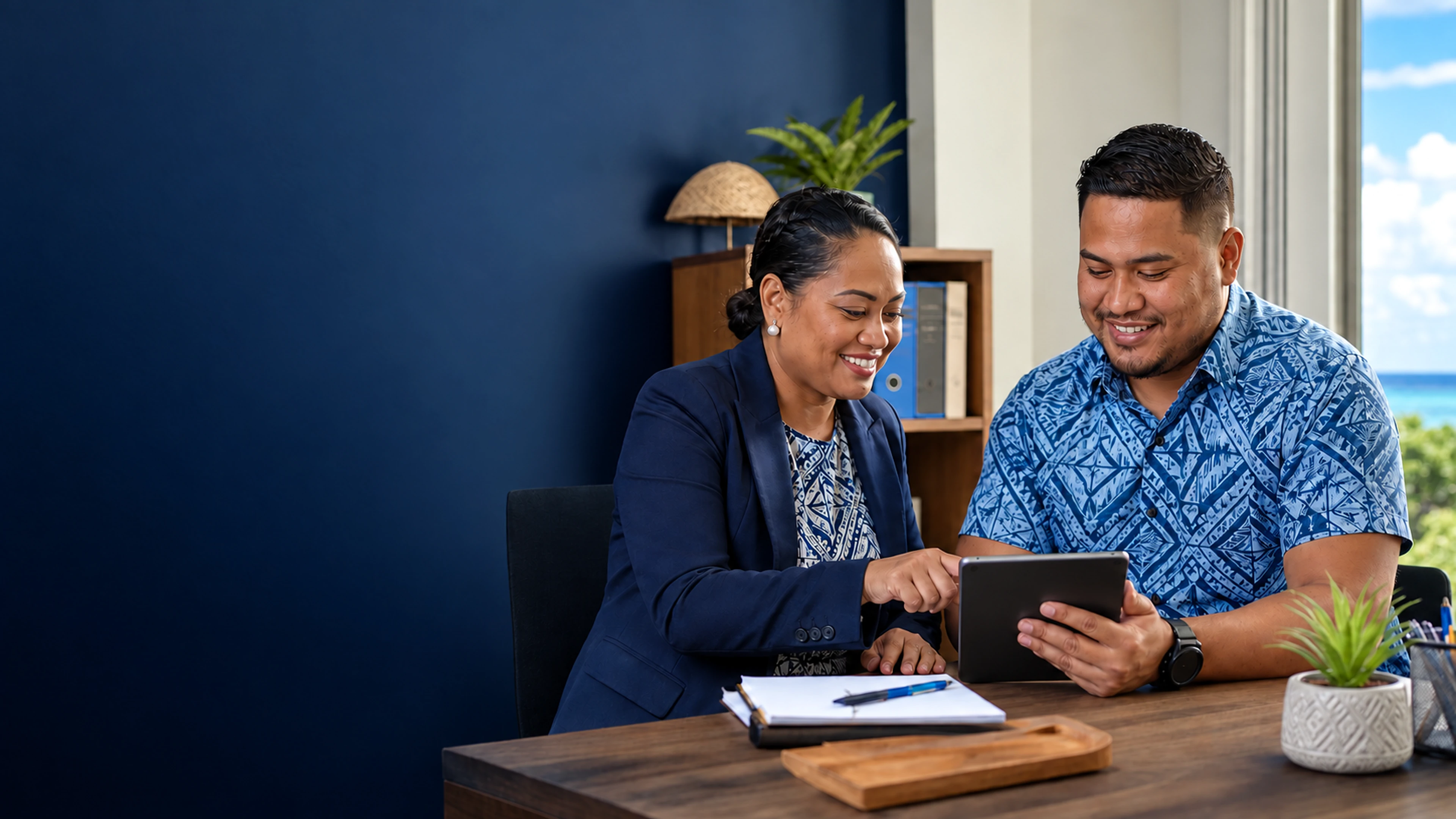 Pacific Islander manager and employee reviewing a salary-loan benefit on a tablet